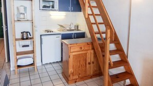 A compact kitchen with a wooden ladder, a microwave, a sink, and cabinets. - Les Roches Bleues by Interhome (Collioure)
