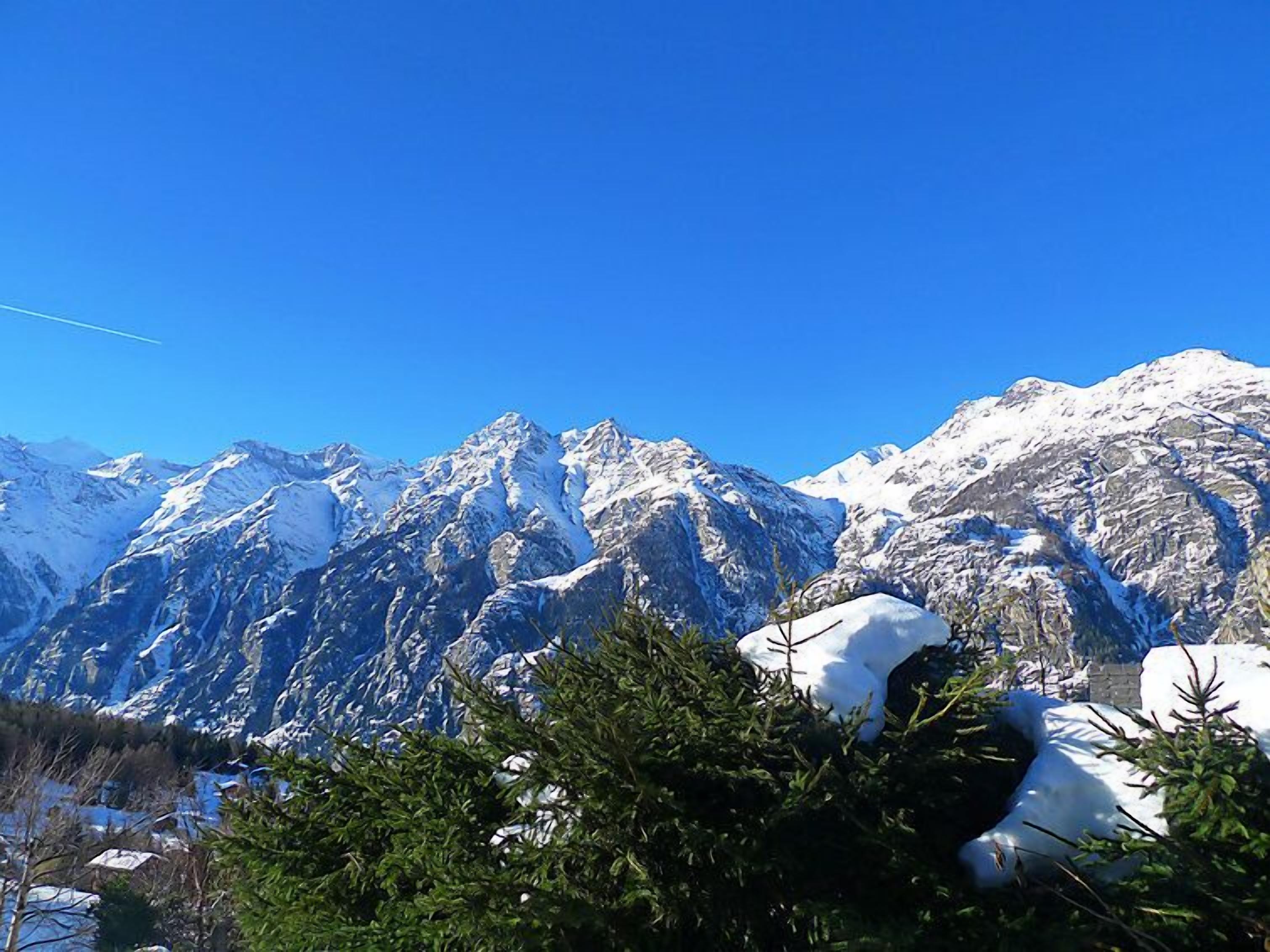 A mountain landscape with snow-covered peaks and a clear blue sky.