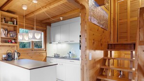 A wooden cabin interior with a kitchen area, wooden shelves, and a window with a view of trees. - Rietsli by Interhome (Grächen)