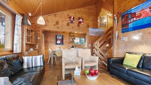A cozy log cabin interior with a dining area, a sofa, a coffee table with fruit, and a staircase. - Rietsli by Interhome (Grächen)