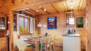 A wooden cabin interior with a dining area, kitchen, and a view of the outdoors. - Rietsli by Interhome (Grächen)