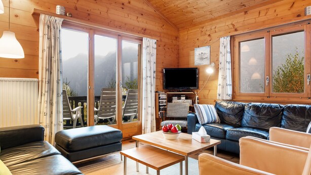 A cozy wooden cabin interior with a sofa, a table with fruit, and a TV. - Rietsli by Interhome (Grächen)