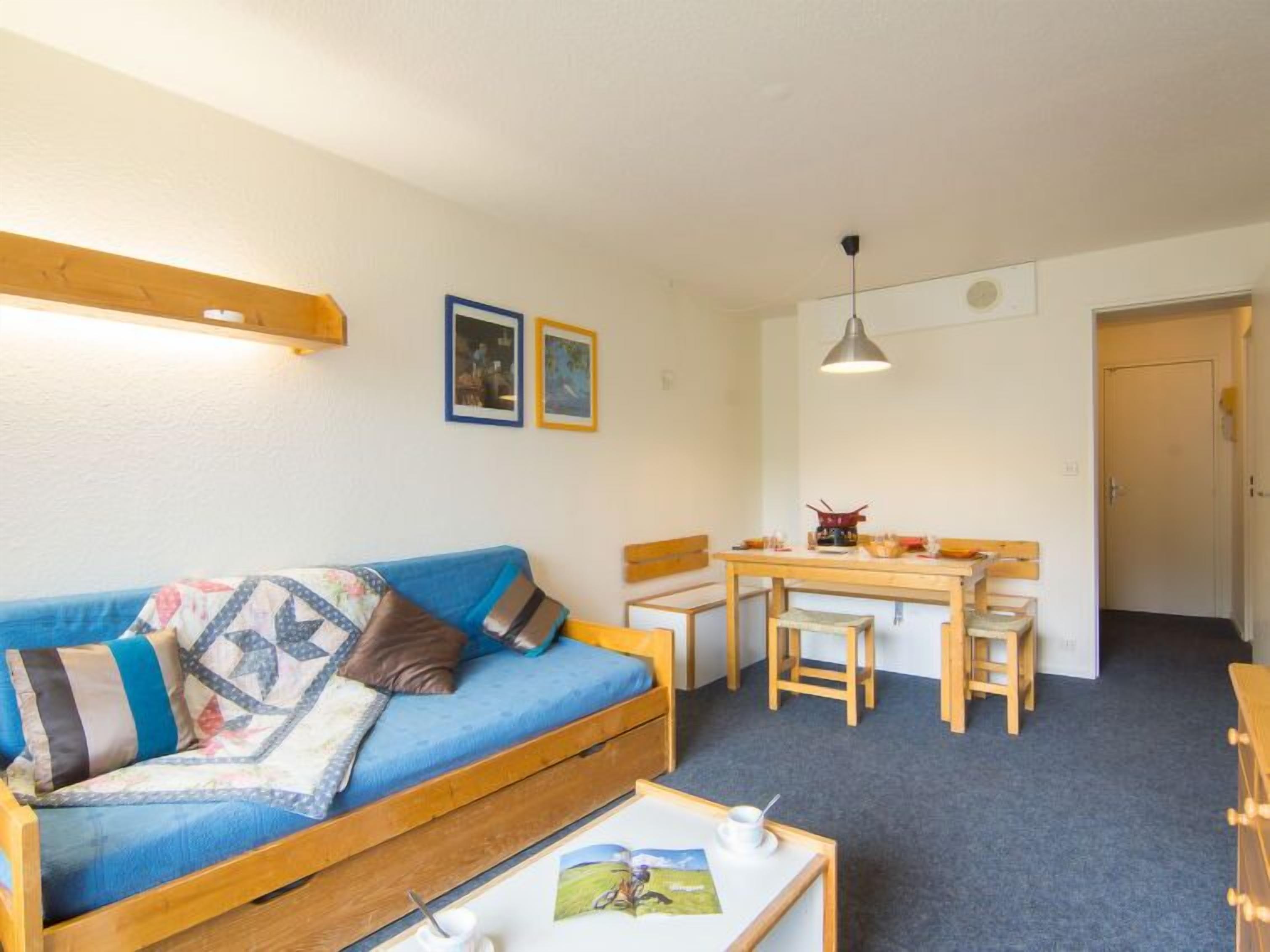 Een gezellige kamer met een blauwe bank, een houten eettafel en stoelen.
