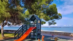 Ein Spielplatz mit Rutsche und Schaukeln in der Nähe von Wasser.