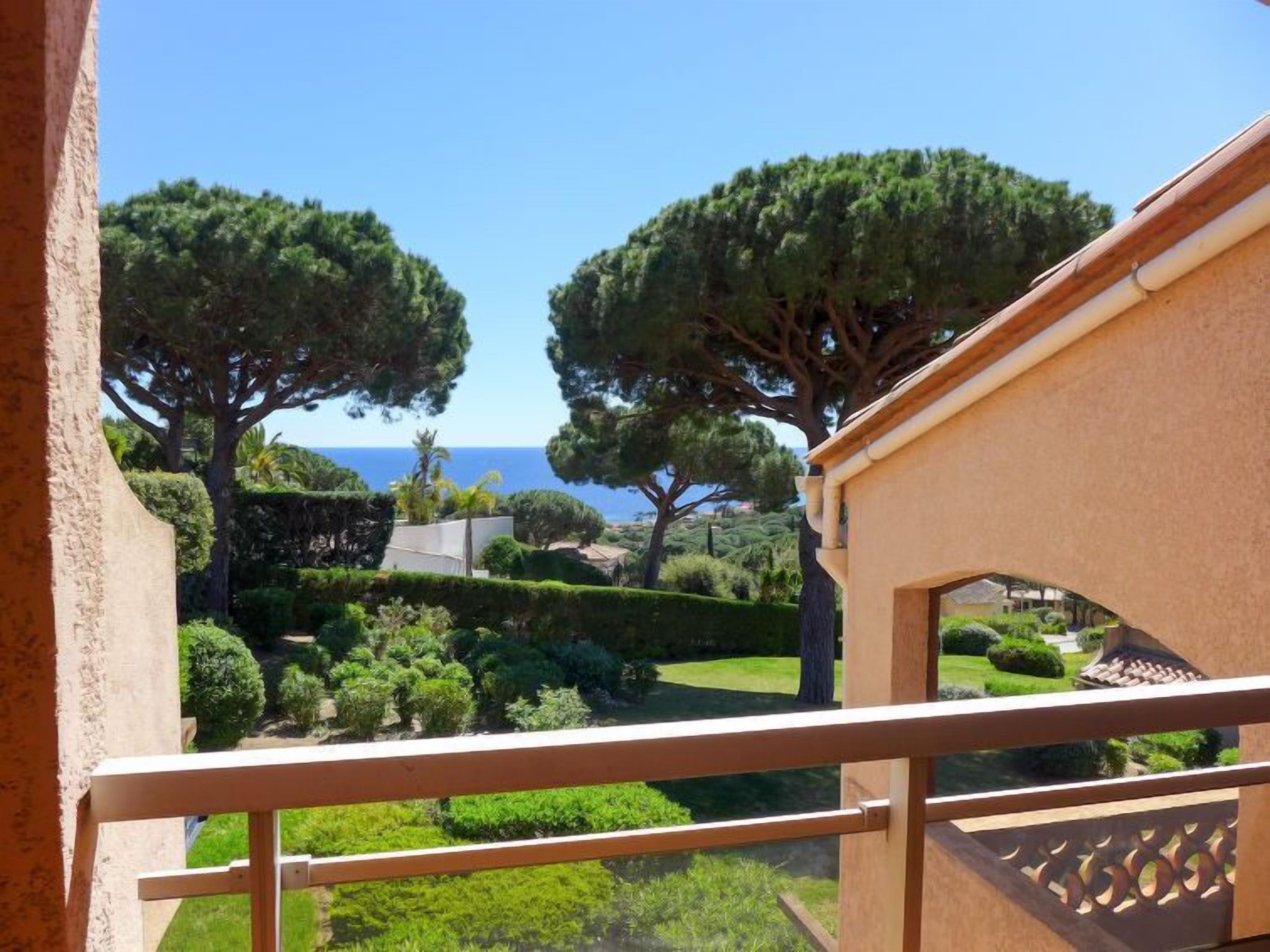 Ein Balkon mit Blick auf einen gepflegten Garten und das Meer.