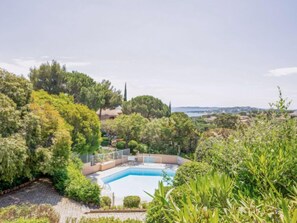 A pool surrounded by lush greenery and a view of the sea.