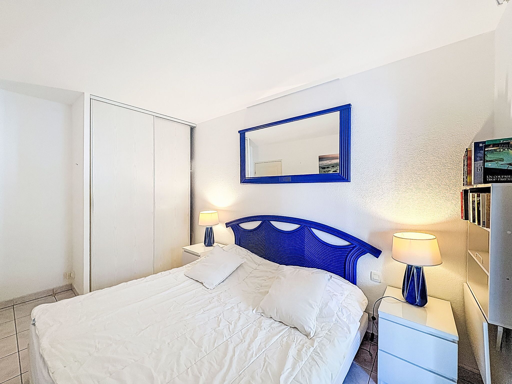 Een hotelkamer met een bed, een kledingkast, een spiegel en een nachtkastje met lampen.