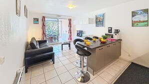 Un espace de vie compact comprenant un coin cuisine, un coin repas avec une table et des chaises, et un canapé.
