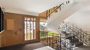 A modern interior with a wooden door, a staircase with black wrought iron railings, and a view of the outside. - Eldorado 321 by Interhome (Verbier)
