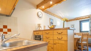 Une cuisine avec un meuble en bois, un évier et une horloge au mur.