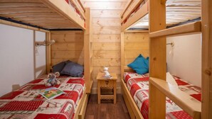 Une petite pièce en bois, dotée de lits superposés, chacun ayant une petite table de chevet et des oreillers.