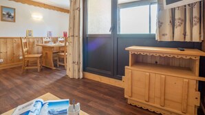 Une pièce confortable, dotée de meubles en bois, d’une grande fenêtre et d’un téléviseur.