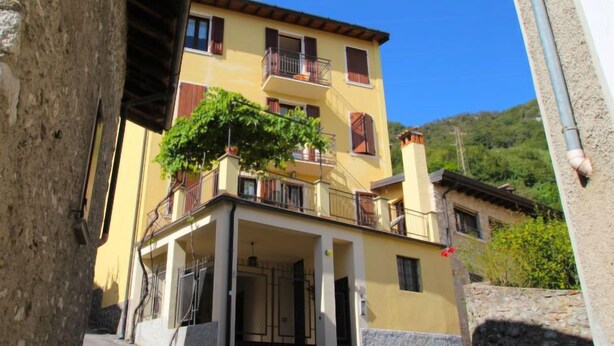 A two-story building with a balcony and a tree in front.