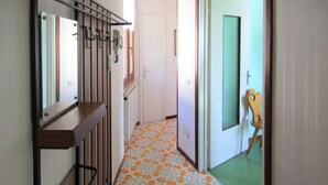A hallway with patterned flooring, a wooden bench, and a door with a green window.