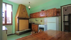 A kitchen with wooden cabinets, a white refrigerator, a stove, and a dining table.