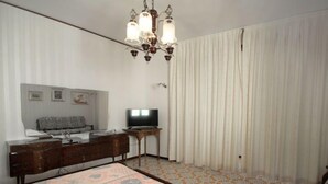 A bedroom with a bed, a dresser, a television, and a chandelier.