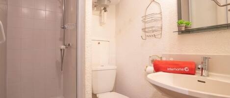 A bathroom with a glass-enclosed shower, a toilet, and a sink with a towel.