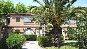 Un edificio con techo de tejas, una palmera y un camino que lleva a un garaje.