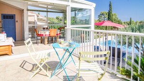 A covered outdoor area with a pool, a dining table with chairs, and a blue umbrella. - Les Hauts de Palayson by Interhome (Le Muy)