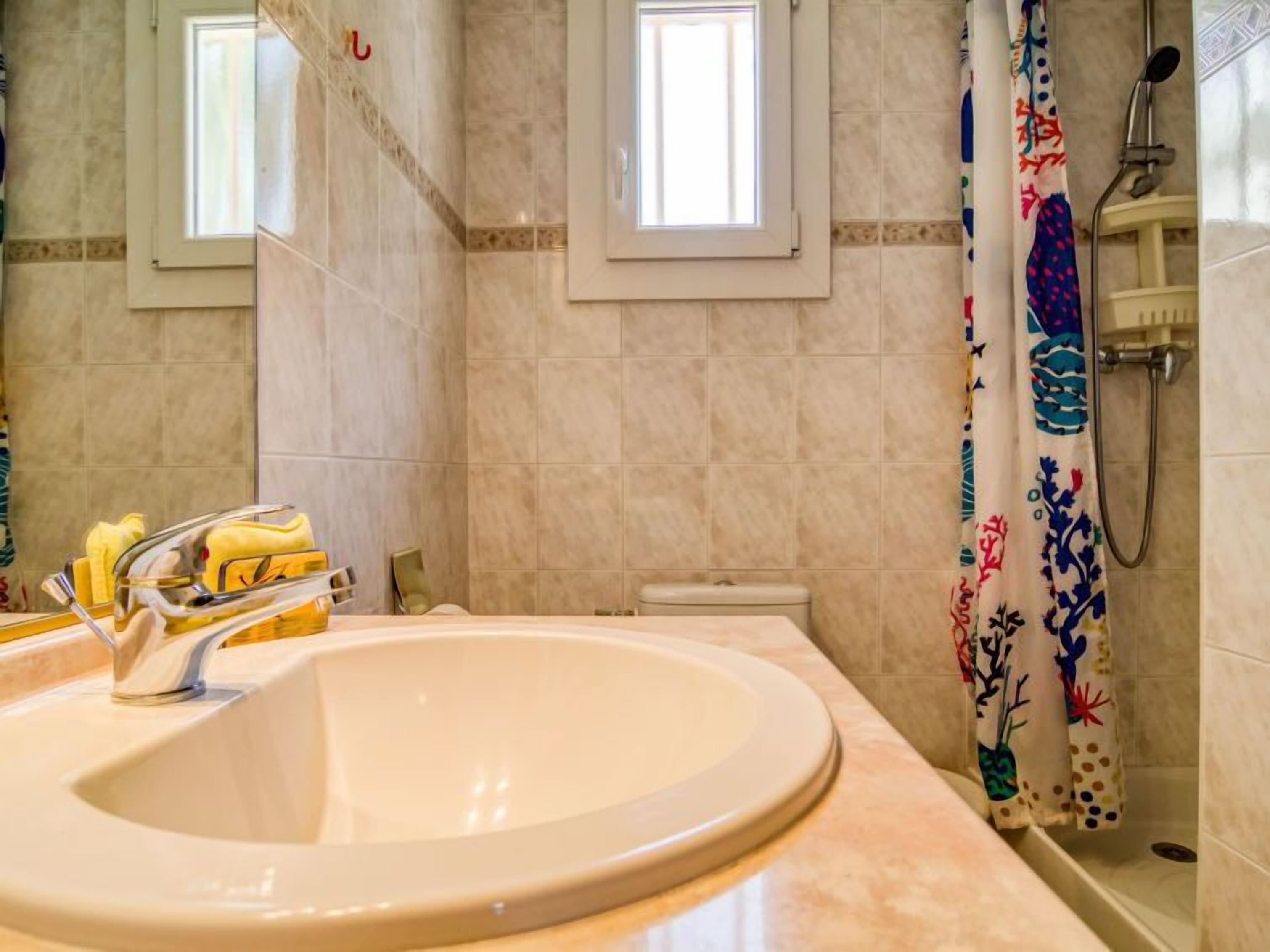 A bathroom with a large sink, a shower, and a window.