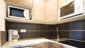 Una cocina compacta con microondas, cafetera y refrigerador.