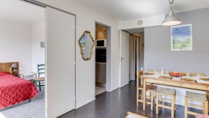Una habitación de hotel compacta con cama, escritorio y zona de comedor.