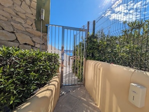 A gated entrance with a stone wall, a metal gate, and a Jotel self-service machine.