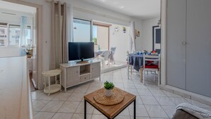 Ein modernes Wohnzimmer mit Flachbildfernseher, einem Essbereich mit Tisch und Stühlen sowie einem großen Kleiderschrank.