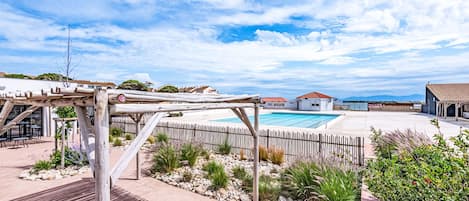 Ein Garten mit Pool, einer Holzpergola und Blick auf Häuser im Hintergrund.