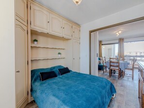 Une chambre à coucher comprenant un lit, une armoire et un balcon avec une table et des chaises.