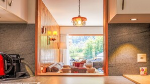 A modern kitchen with a granite countertop, a stove, and a hanging light fixture. - Les Platanes E3 by Interhome (Nendaz)
