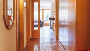 A wooden hallway with a tiled floor leading to a room with a large window. - Les Platanes E3 by Interhome (Nendaz)