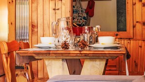 A wooden dining table with a pitcher, glasses, and plates, set in a room with wooden walls and a mirror. - Les Platanes E3 by Interhome (Nendaz)