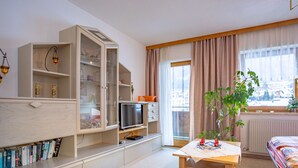 A well-lit room with a wooden table, a bookshelf, a TV, and a window with curtains. - Bichleregg by Interhome (Ötz)