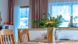 A dining area with a table set for two, a wooden chair, and a vase with greenery. - Bichleregg by Interhome (Ötz)