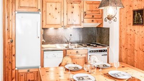 A kitchen with wooden cabinets, a Bosch dishwasher, a stove, and a dining table set with plates and glasses. - Grand Place 5 by Interhome (Nendaz)
