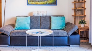 A modern living room with a sofa, a coffee table, and a painting of a mountainous landscape. - Grand Panorama A11 by Interhome (Nendaz)