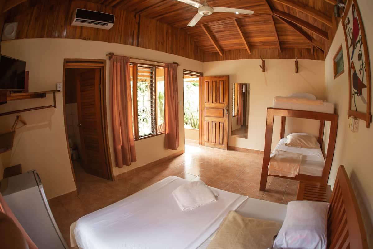 A cozy room with a bed, a bunk bed, a ceiling fan, and a window with curtains.