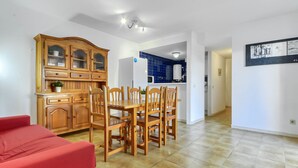 A spacious living area with a dining table and chairs, a red sofa, and a kitchen with blue tiles and wooden cabinets. - Platja de Roses by Interhome (Roses)