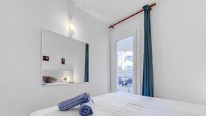 A hotel room with a large bed, a bedside table with a lamp, a mirror, and a view of the outside balcony. - Platja de Roses by Interhome (Roses)