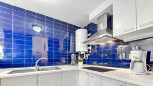 A modern kitchen with blue tiles, white cabinets, a stainless steel sink, and a coffee maker. - Platja de Roses by Interhome (Roses)