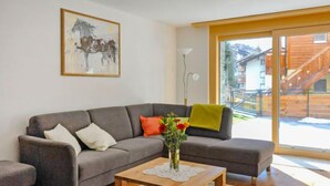 A modern living room with a grey sofa, a wooden coffee table, and a painting of a horse on the wall. - Blauherd by Interhome (Zermatt)