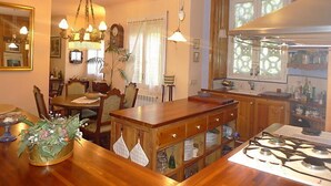 Une cuisine chaleureuse avec des meubles de rangement en bois, une cuisinière à gaz et un coin repas comprenant une table et des chaises en bois.