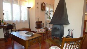 Un salon chaleureux avec une table en bois, des chaises, une cheminée et une horloge au mur.