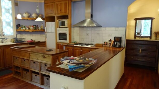 Une cuisine avec des meubles en bois, un îlot central, une cuisinière et un four à micro-ondes.