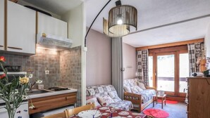 A compact living space with a kitchenette, dining area, and a bedroom with a window.