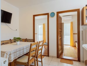 Un comedor con una mesa, sillas, una planta y un reloj en la pared.