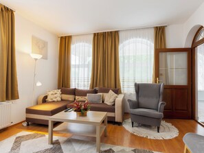 A living room with a sofa, armchair, coffee table, and a lamp.