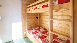 Dormitorio con literas, paredes de madera y una puerta.