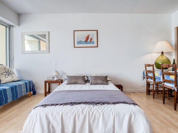A bedroom with a bed, bedside tables, a lamp, a chair, and a framed picture on the wall.
